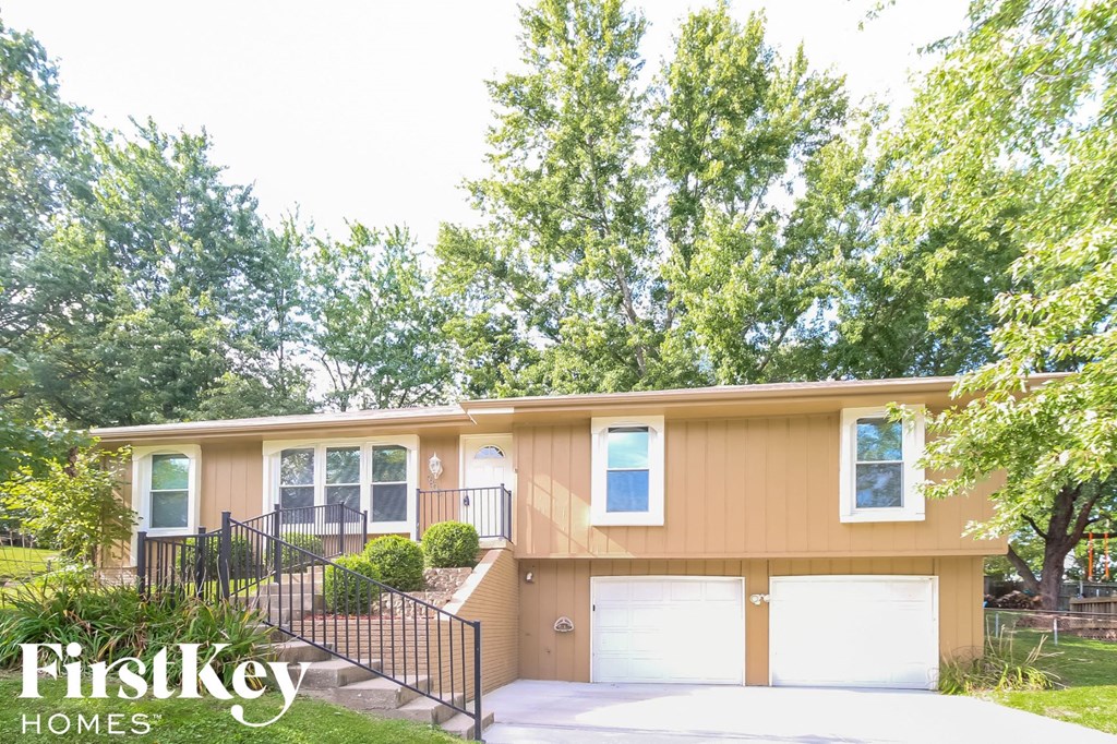 a yellow house with two garage doors and a driveway