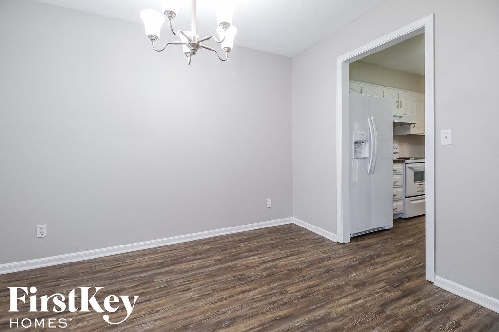 the living room of an empty house with wood flooring and a refrigerator