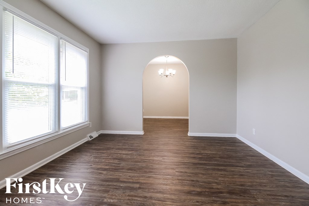 a living room with wood floors and white walls and an arched window