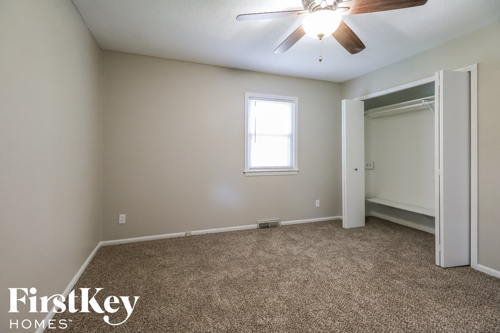 a empty room with a ceiling fan and a door to a closet