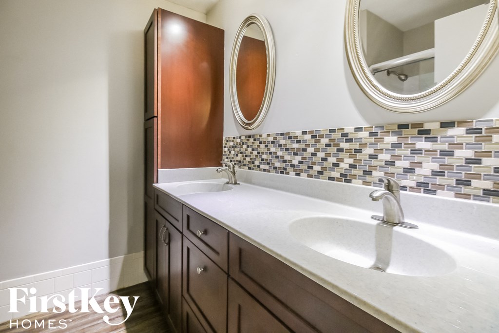 a bathroom with a sink and two mirrors and a shower