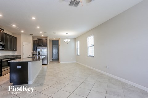 A spacious kitchen with a black fridge and a dining area with a table and chairs.