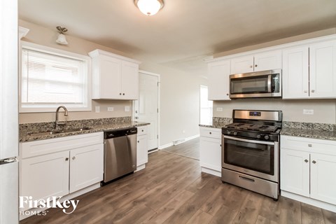 A kitchen with white cabinets and a stainless steel dishwasher and oven.