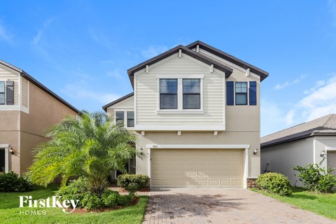 a house with a garage door and a palm tree in front of it