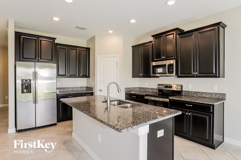 a kitchen with black cabinets and granite counter tops and stainless steel appliances