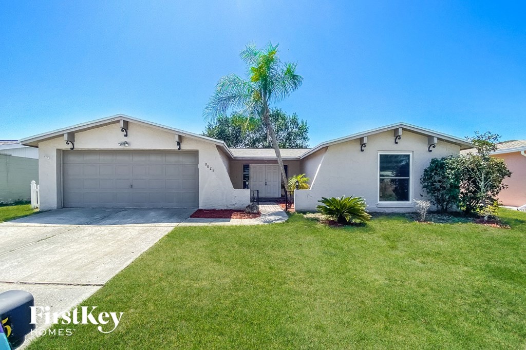 A house with a garage and a tree in front of it.