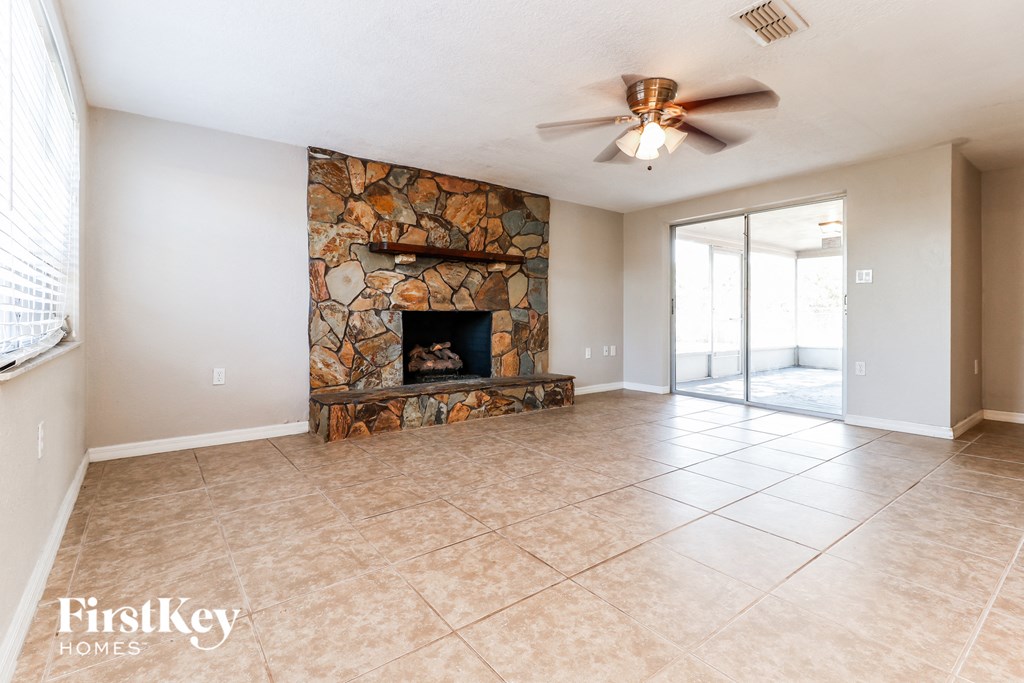 A spacious living room with a stone fireplace and sliding glass doors.