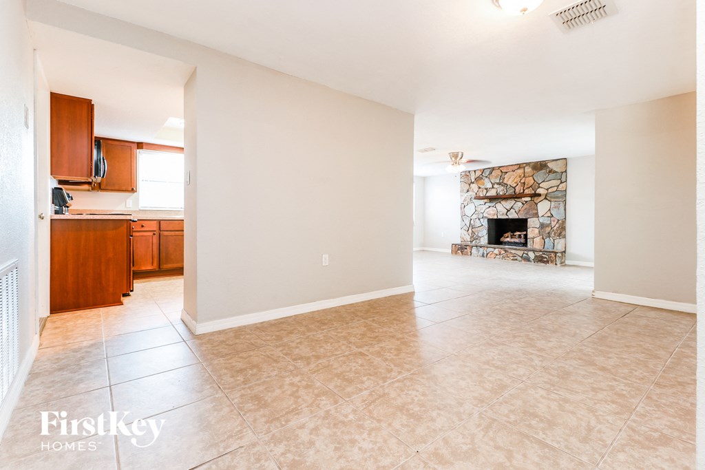 A spacious living room with a fireplace and a kitchen area in the background.