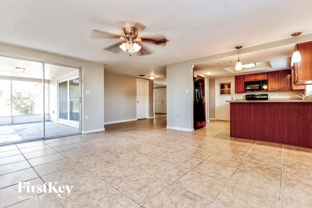 A spacious living room with a kitchen area in the background.