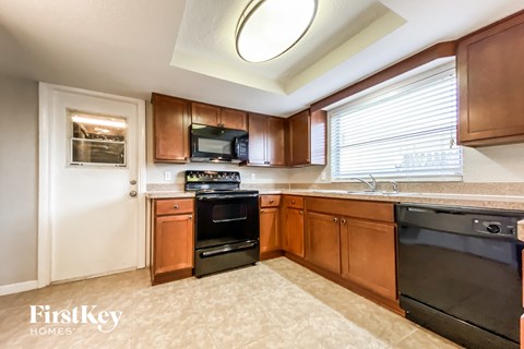 A kitchen with a black oven and brown cabinets.