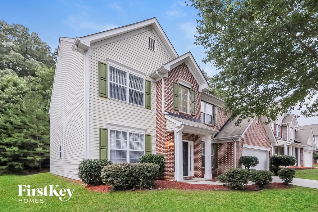 a white house with green shutters and a lawn and trees