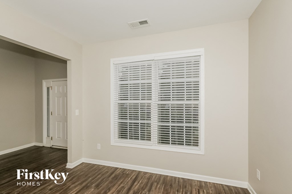 the living room of an apartment with a large window and wood flooring
