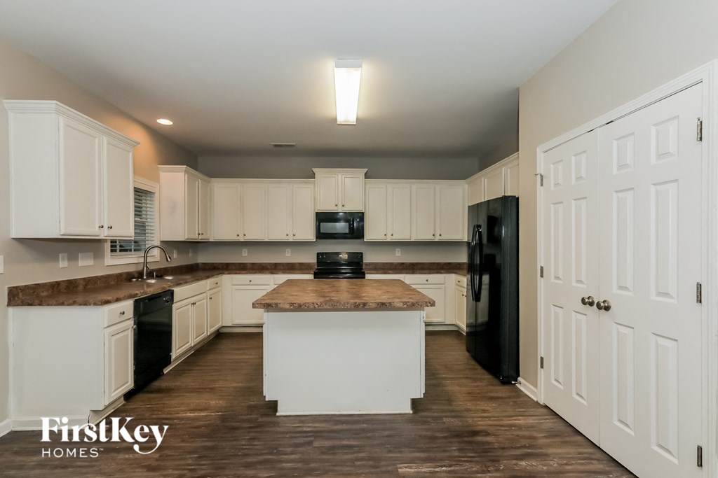 a kitchen with white cabinets and black appliances and a counter top