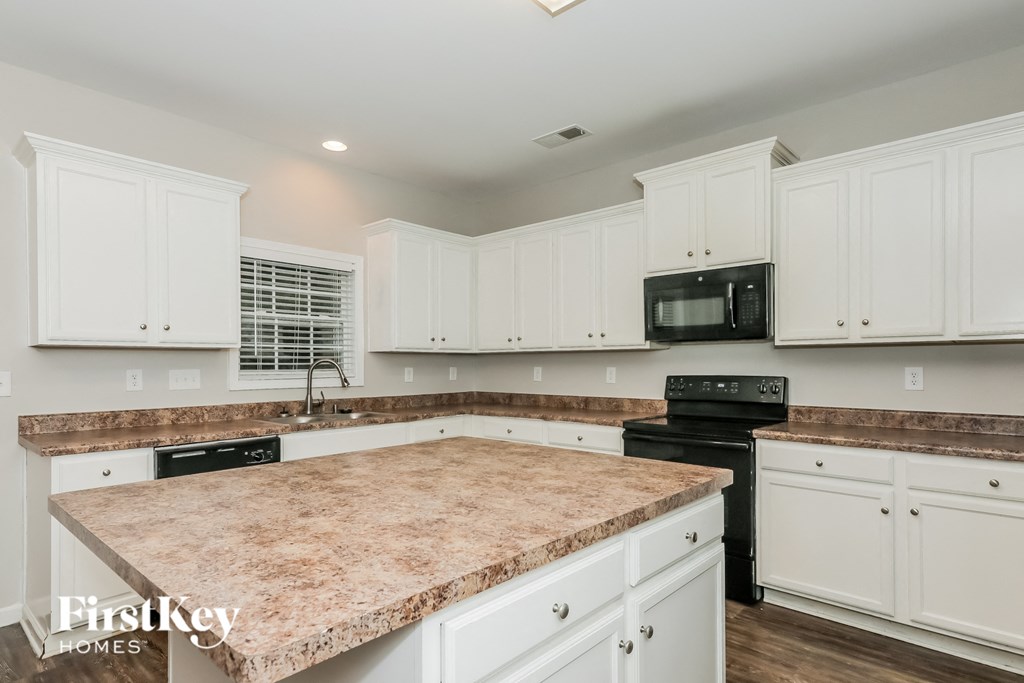a large kitchen with white cabinets and granite counter tops