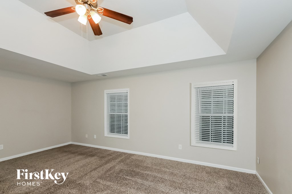 the living room has a ceiling fan and two windows