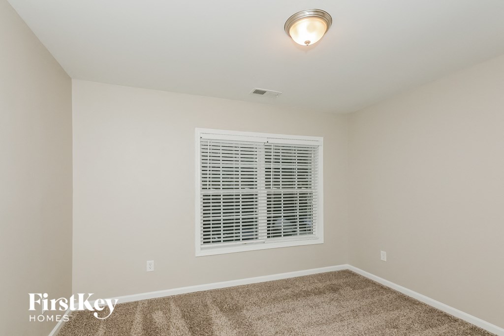 a bedroom with a window and a carpeted floor