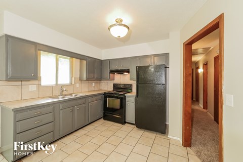 A kitchen with a black refrigerator and a black oven.