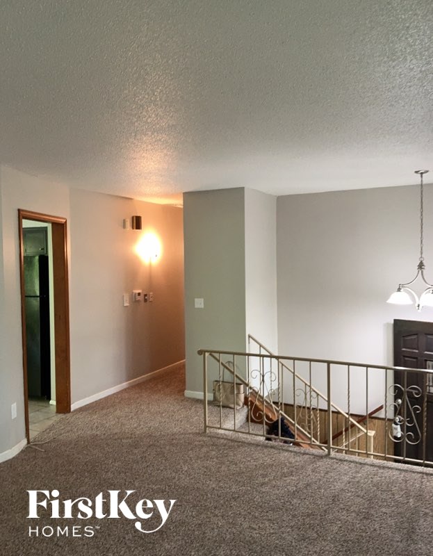 A hallway with a staircase and a light on the wall.
