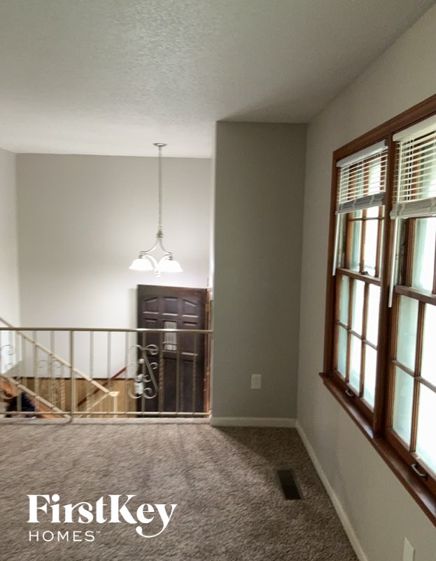 A room with a light hanging from the ceiling and a window with blinds.