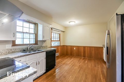 A kitchen with wooden floors and white cabinets.