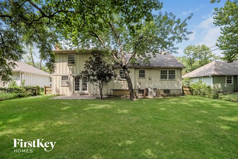 A house with a lawn and trees in front of it.