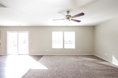 an empty living room with a ceiling fan