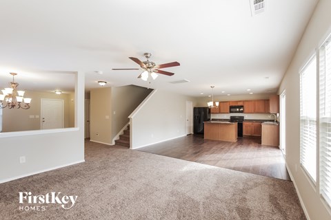 an empty living room and kitchen with a ceiling fan