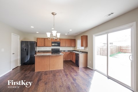 a kitchen with wooden cabinets and black appliances and a sliding glass door