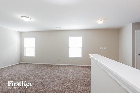 a bedroom with white walls and carpet and a white staircase