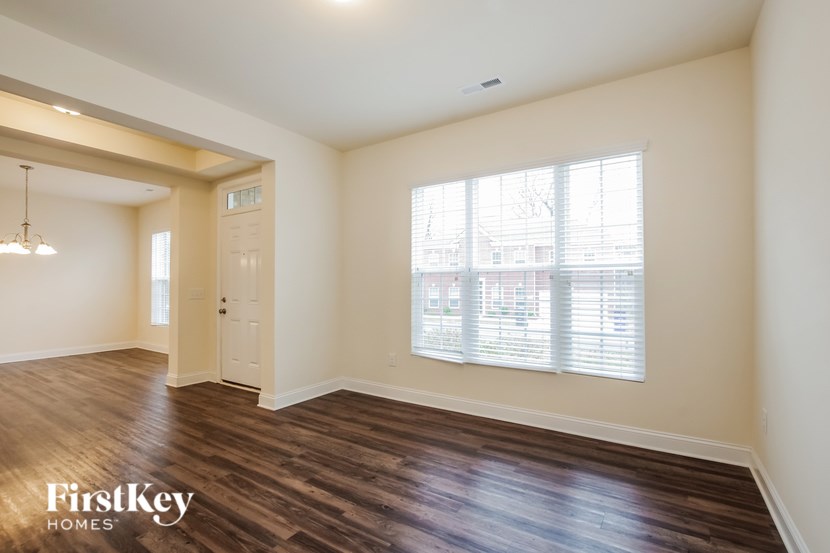 A room with wooden floors and a large window with blinds.