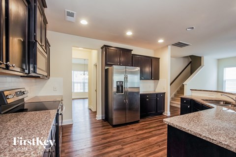 A kitchen with dark wood cabinets and a granite countertop.
