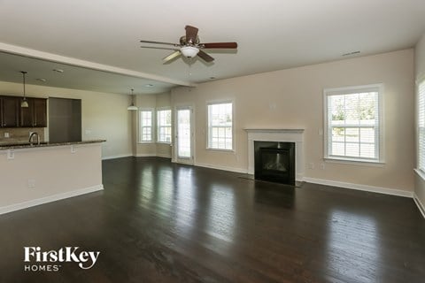A spacious living room with a fireplace and a ceiling fan.