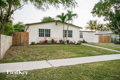 a white house with a lawn and palm trees