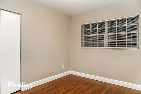 a bedroom with a window and wooden floors and a white door