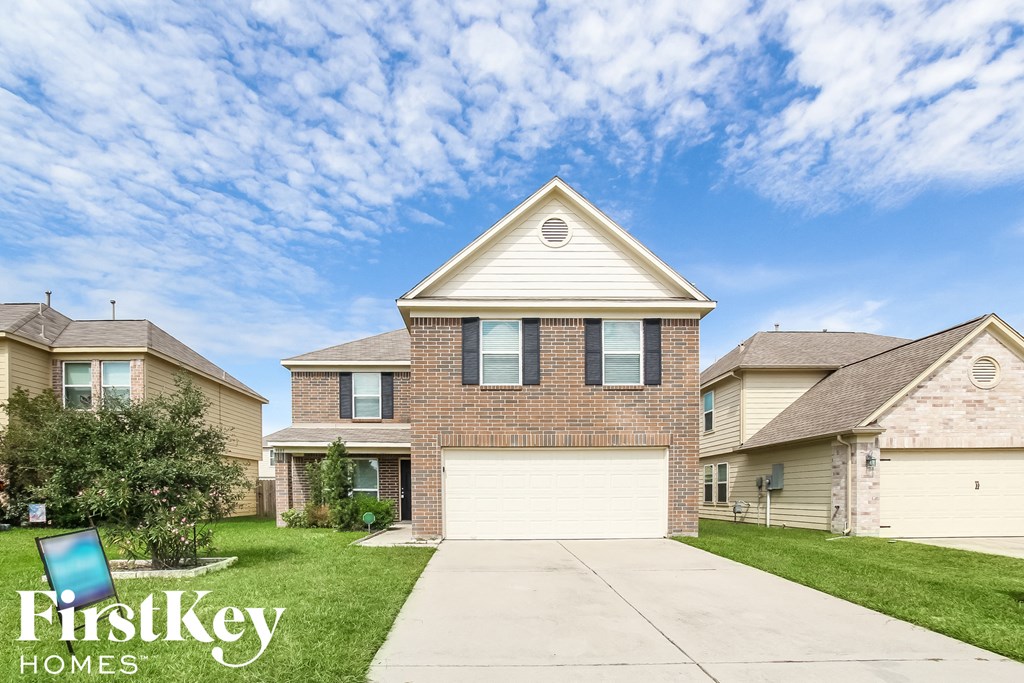 a brick house with a white garage door in front of a lawn