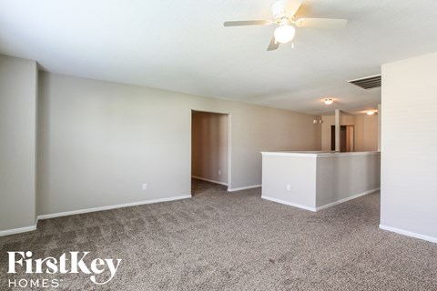 a living room with carpet and a ceiling fan