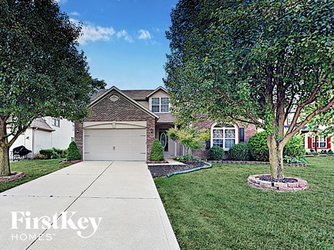 a home with a white garage door and a lawn and trees