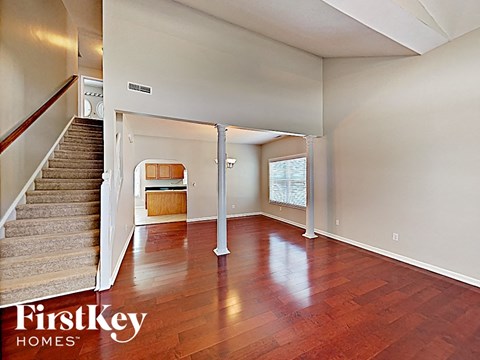 an empty living room with wood floors and a staircase