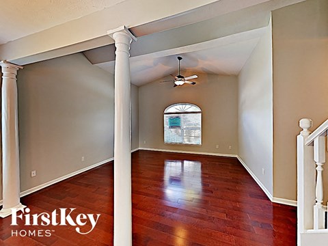 an empty living room with wood floors and a ceiling fan