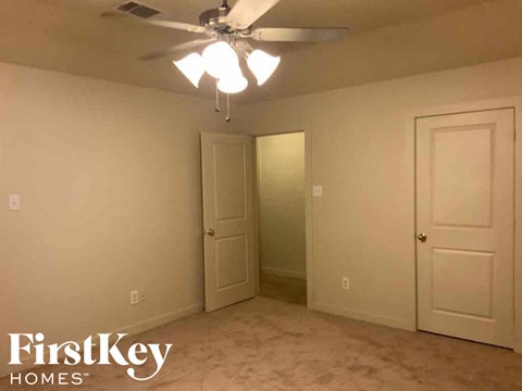 a bedroom with a ceiling fan and a door to a closet