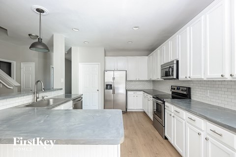 a white kitchen with stainless steel appliances and marble counter tops