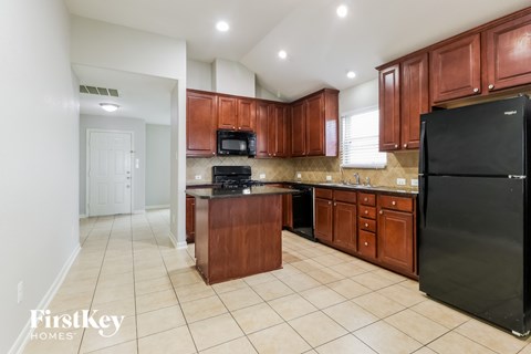 A kitchen with brown cabinets and a black refrigerator.