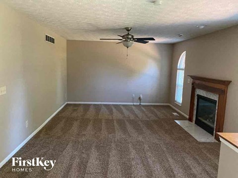 A spacious room with a fireplace and a ceiling fan.
