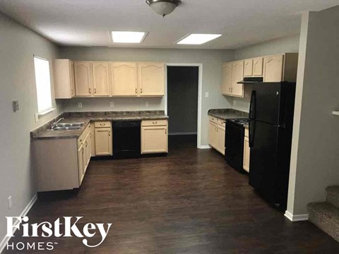 A kitchen with black appliances and wooden floors.