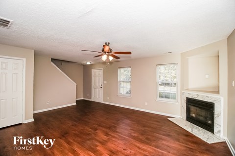 A spacious living room with wood flooring and a fireplace.