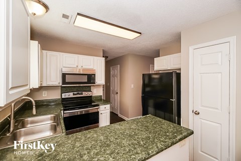 A kitchen with a granite counter top and a refrigerator.