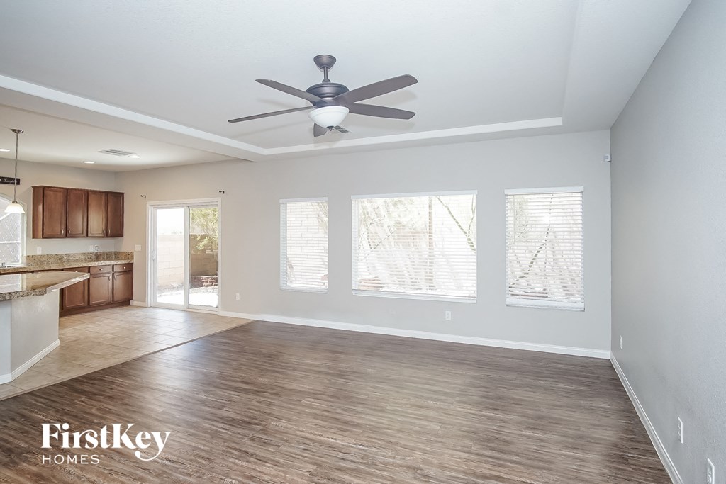 an empty living room and kitchen with a ceiling fan