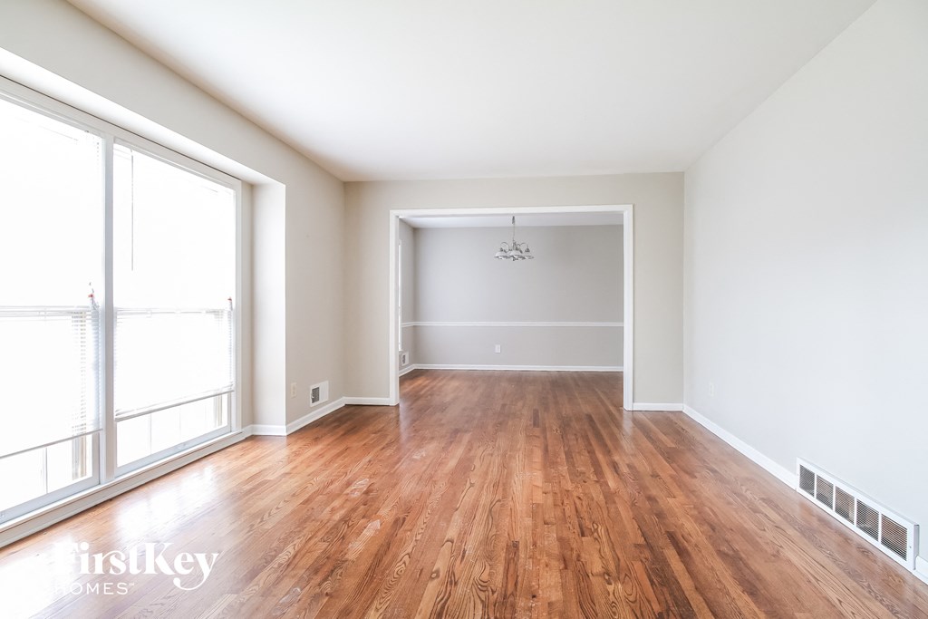 an empty living room with wood floors and white walls