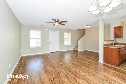 A spacious room with wooden floors and a ceiling fan.