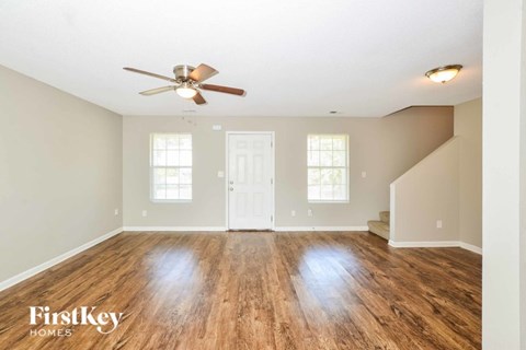 A spacious room with wooden floors and a ceiling fan.